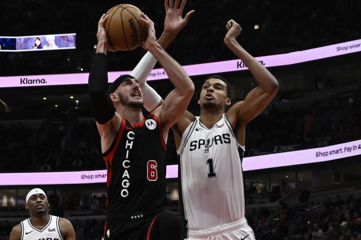 Dec 21, 2023; Chicago, Illinois, USA;  Chicago Bulls guard Alex Caruso (6) shoots against San Antonio Spurs center Victor Wembanyama (1) during the first half at the United Center.