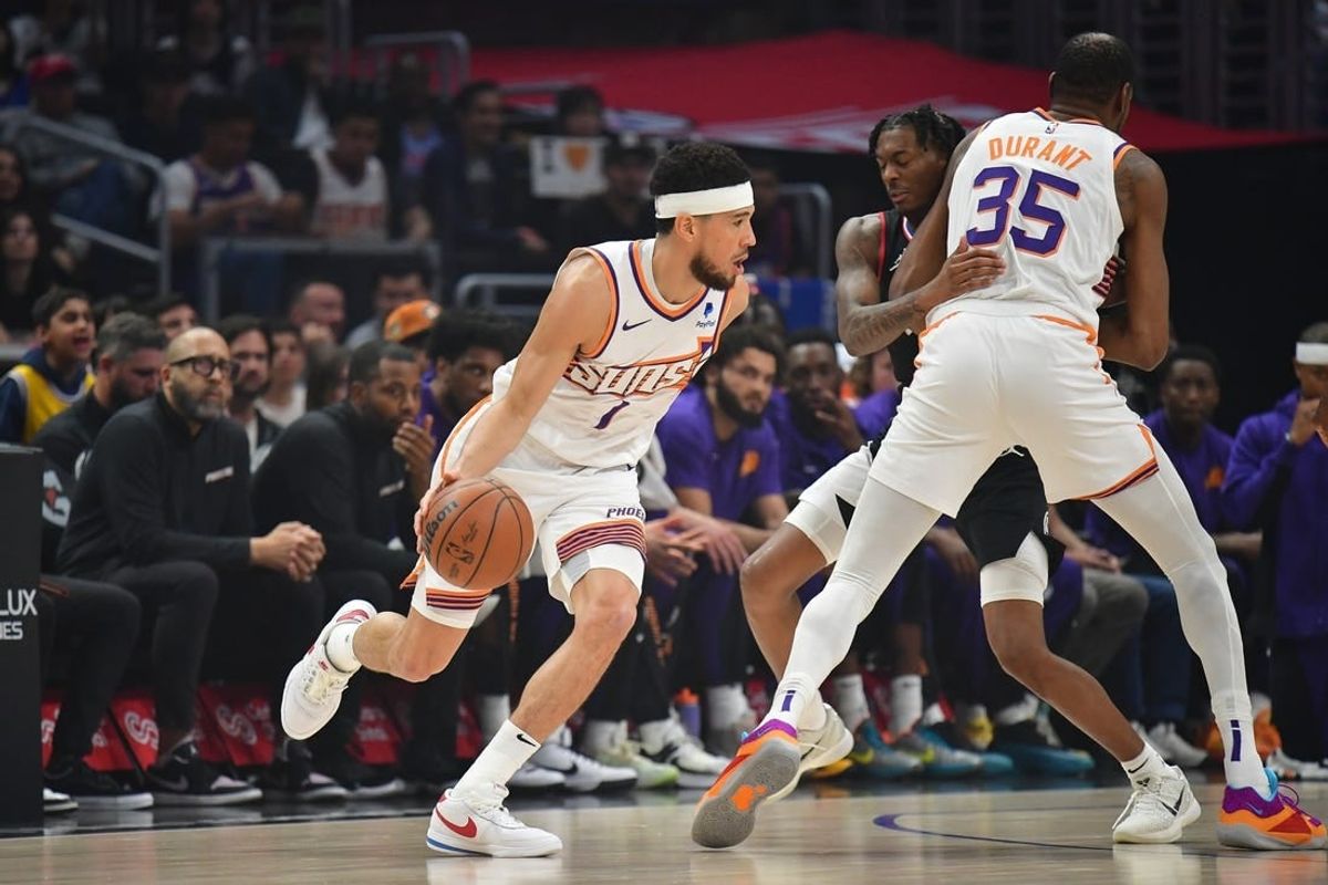 Apr 10, 2024; Los Angeles, California, USA; Phoenix Suns guard Devin Booker (1) moves the ball as forward Kevin Durant (35) provides coverage against Los Angeles Clippers guard Bones Hyland (5) during the first half at Crypto.com Arena.