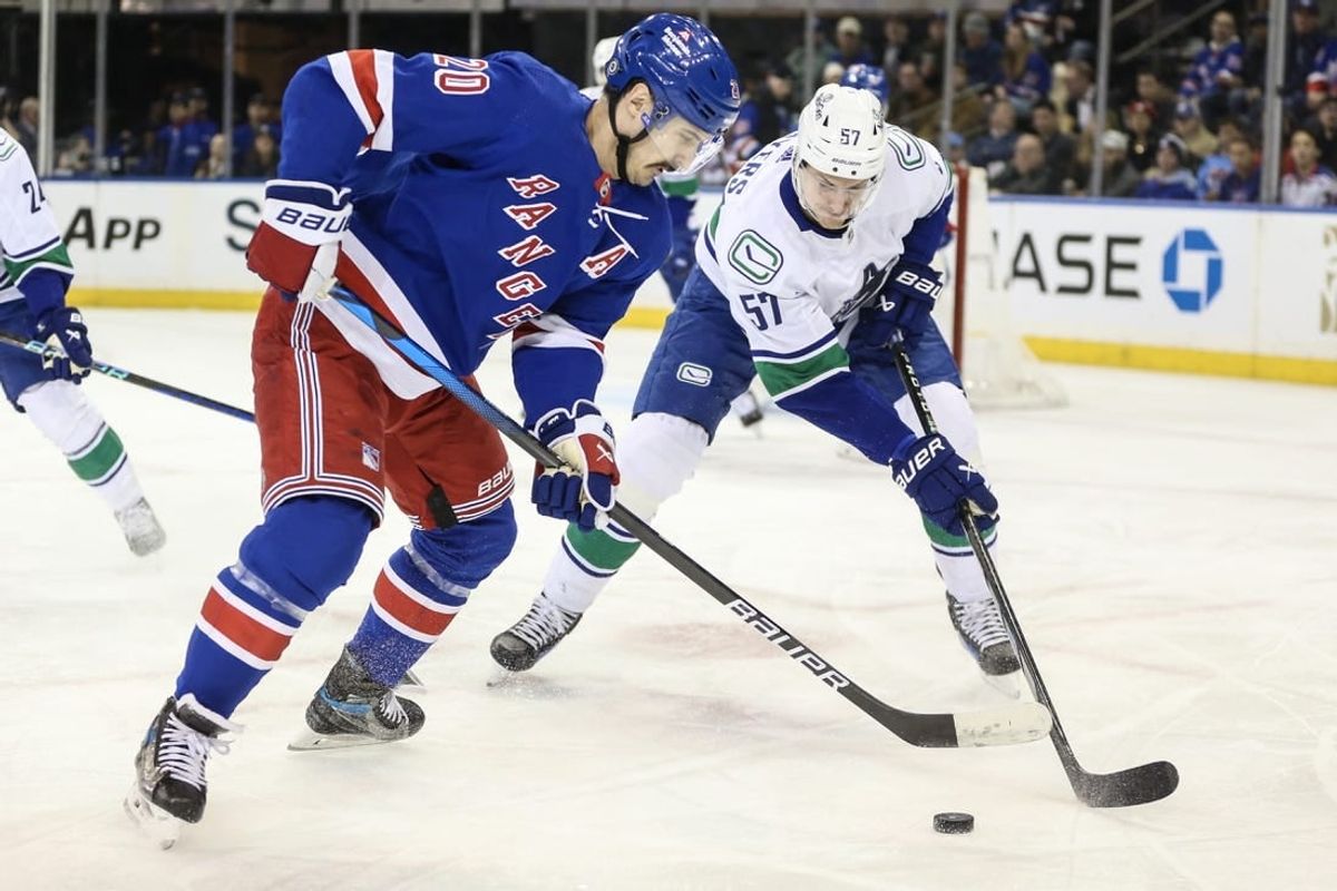 Jan 8, 2024; New York, New York, USA;  New York Rangers left wing Chris Kreider (20) and Vancouver Canucks defenseman Tyler Myers (57) battle for control of the puck in the first period at Madison Square Garden.