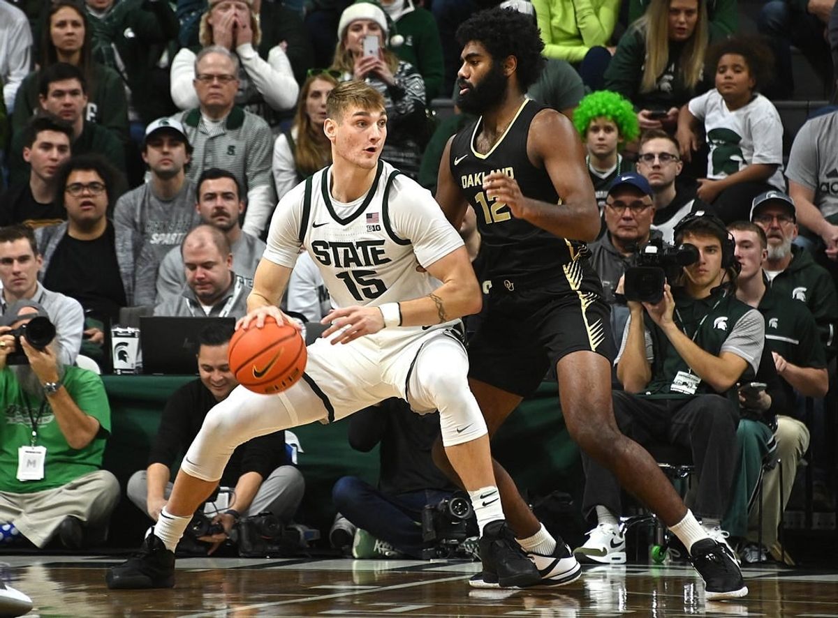Dec 18, 2023; East Lansing, Michigan, USA;   Michigan State Spartans center Carson Cooper (15) dribbles the ball against Oakland Golden Grizzlies forward Tuburu Naivalurua (12) during the first half at Jack Breslin Student Events Center.
