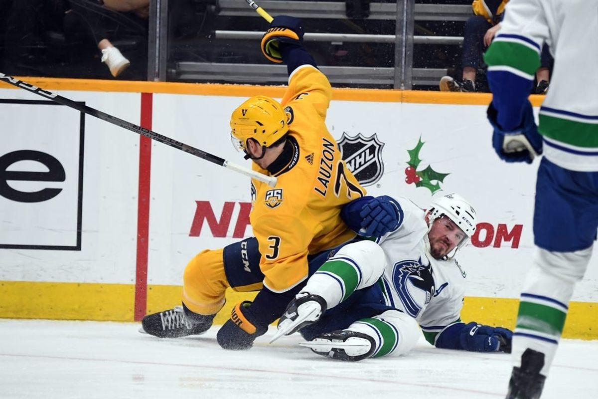 Dec 19, 2023; Nashville, Tennessee, USA; Nashville Predators defenseman Jeremy Lauzon (3) and Vancouver Canucks center J.T. Miller (9) fall to the ice going for a puck in the corner during the second period at Bridgestone Arena.