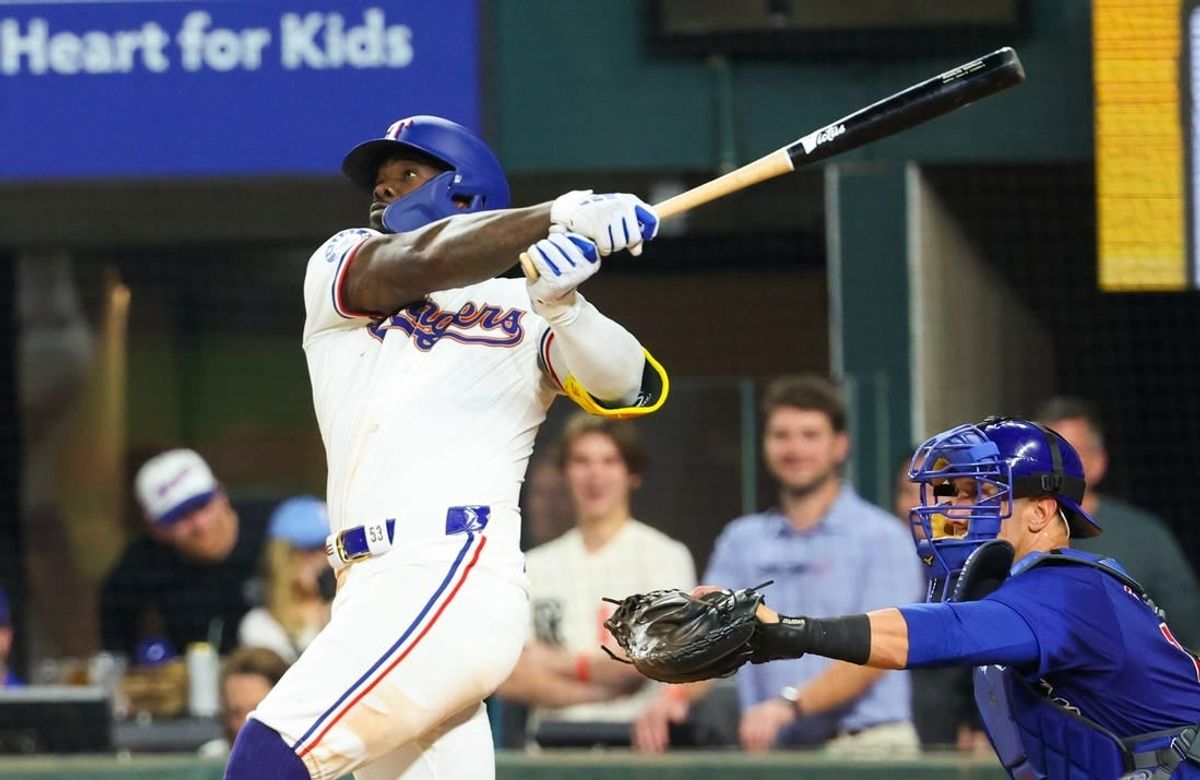 Mar 30, 2024; Arlington, Texas, USA;  Texas Rangers right fielder Adolis Garcia (53) hits a sacrifice fly rbi during the eighth inning against the Chicago Cubs at Globe Life Field.
