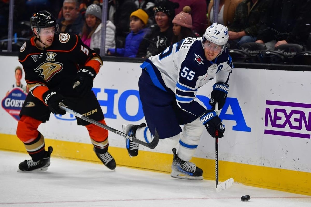 Jan 5, 2024; Anaheim, California, USA; Winnipeg Jets center Mark Scheifele (55) moves the puck ahead of Anaheim Ducks defenseman Urho Vaakanainen (5) during the first period at Honda Center.