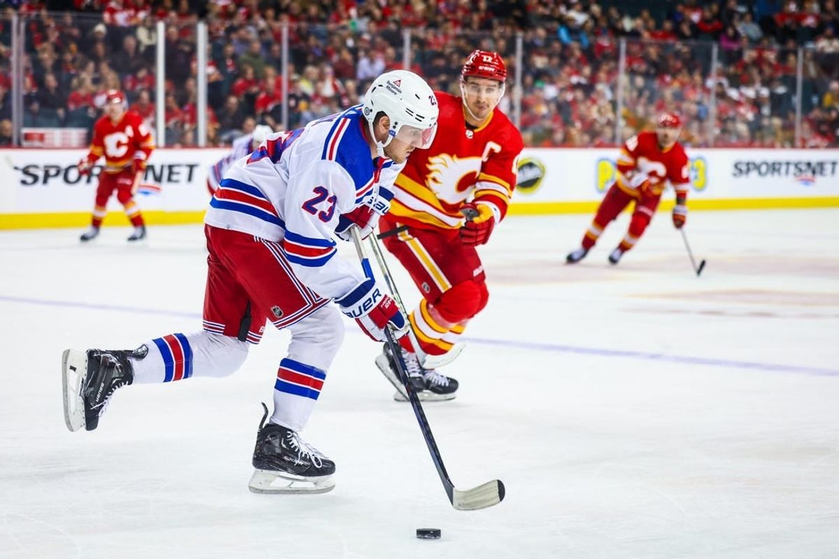 Oct 24, 2023; Calgary, Alberta, CAN; New York Rangers defenseman Adam Fox (23) skates with the puck against the Calgary Flames during the second period at Scotiabank Saddledome.