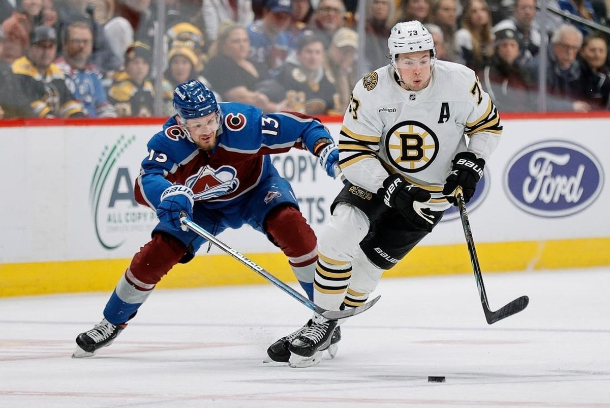 Jan 8, 2024; Denver, Colorado, USA; Boston Bruins defenseman Charlie McAvoy (73) controls the puck ahead of Colorado Avalanche right wing Valeri Nichushkin (13) in the third period at Ball Arena.