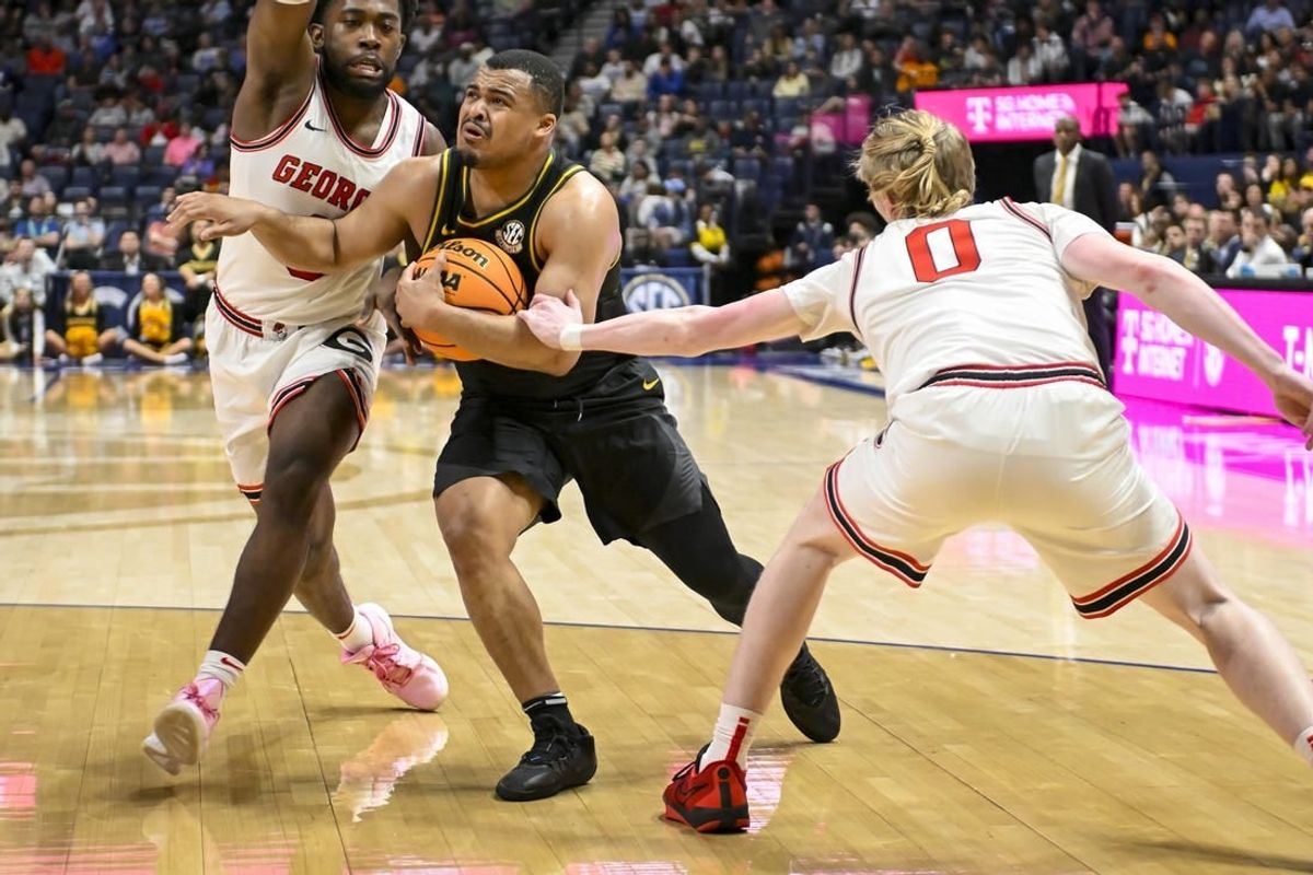 Mar 13, 2024; Nashville, TN, USA;  Missouri Tigers guard Nick Honor (10) splits Georgia Bulldogs guard Blue Cain (0) and forward Jalen DeLoach (23) during the first half at Bridgestone Arena.