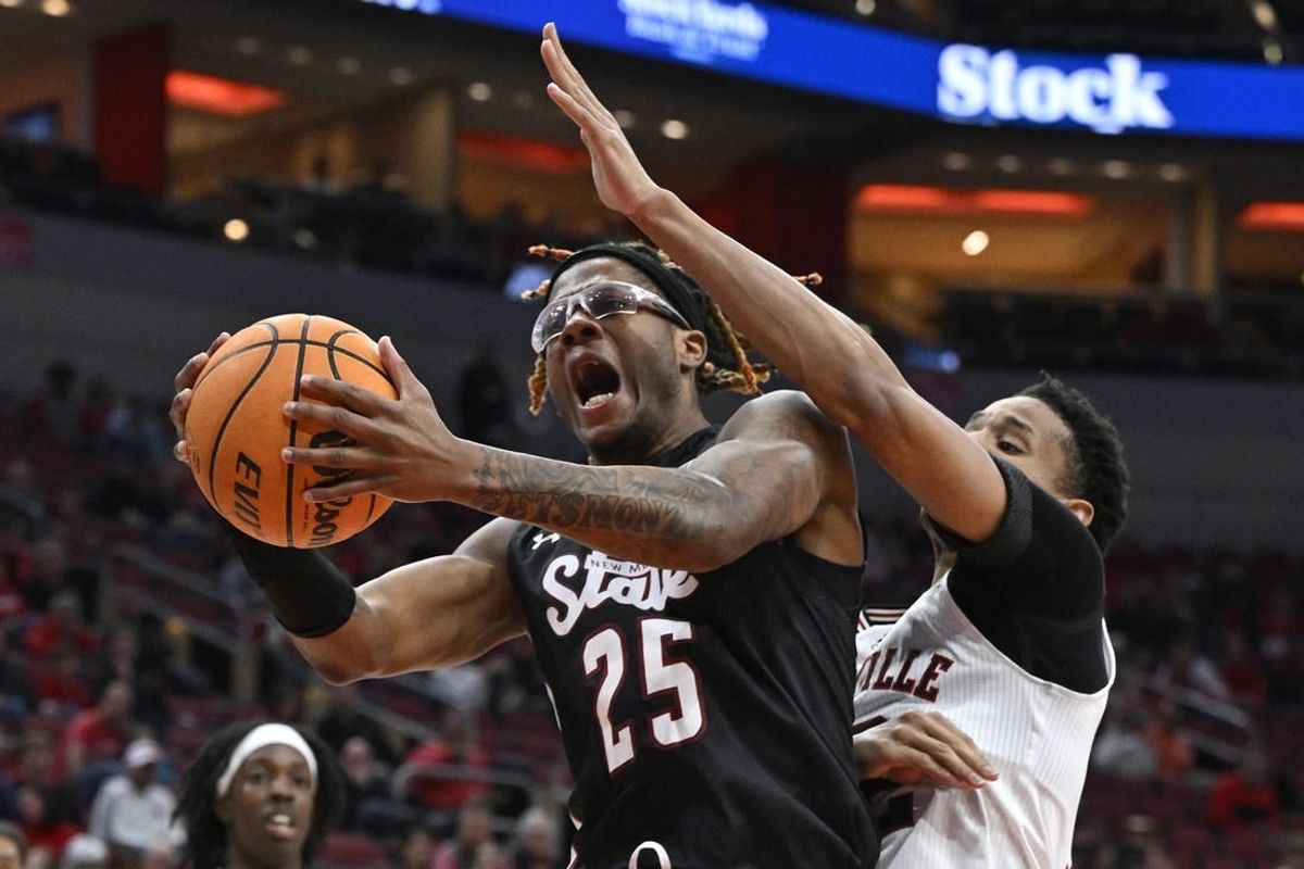 Nov 26, 2023; Louisville, Kentucky, USA; New Mexico State Aggies forward Clarence Jackson (25) attempts to shoot against Louisville Cardinals forward JJ Traynor (12) during the first half at KFC Yum! Center.