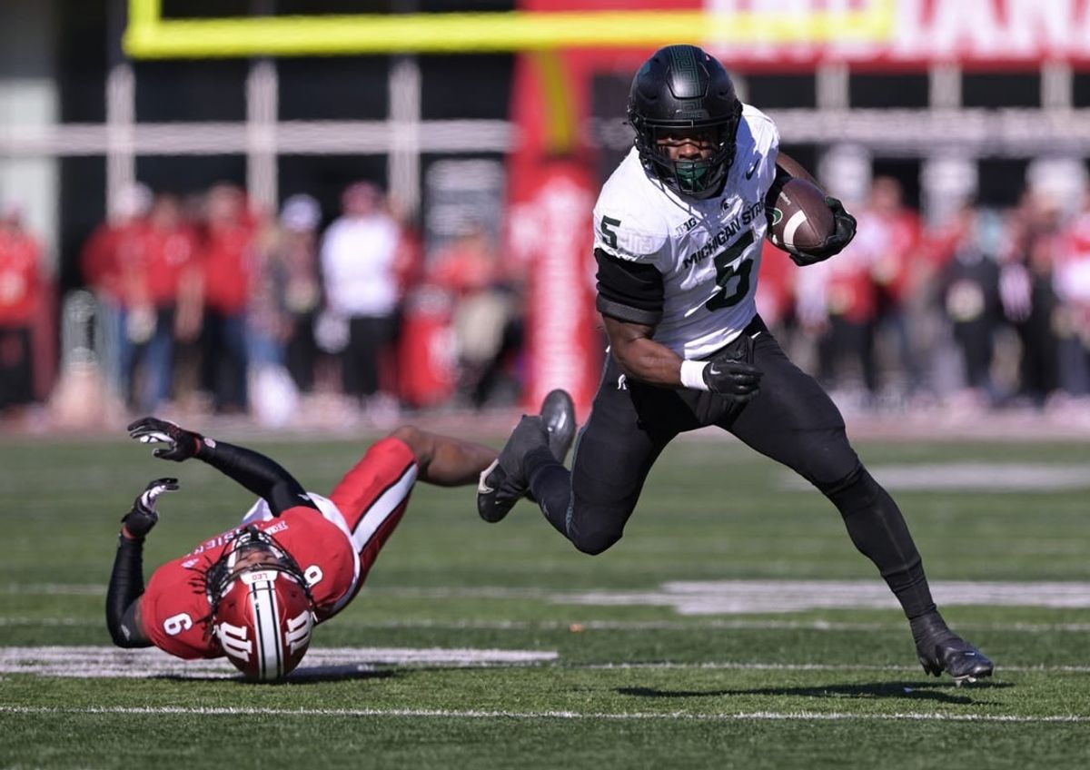 Nov 18, 2023; Bloomington, Indiana, USA;  Michigan State Spartans running back Nathan Carter (5) evades tackle by Indiana Hoosiers defensive back Phillip Dunnam (6) during the first quarter at Memorial Stadium.