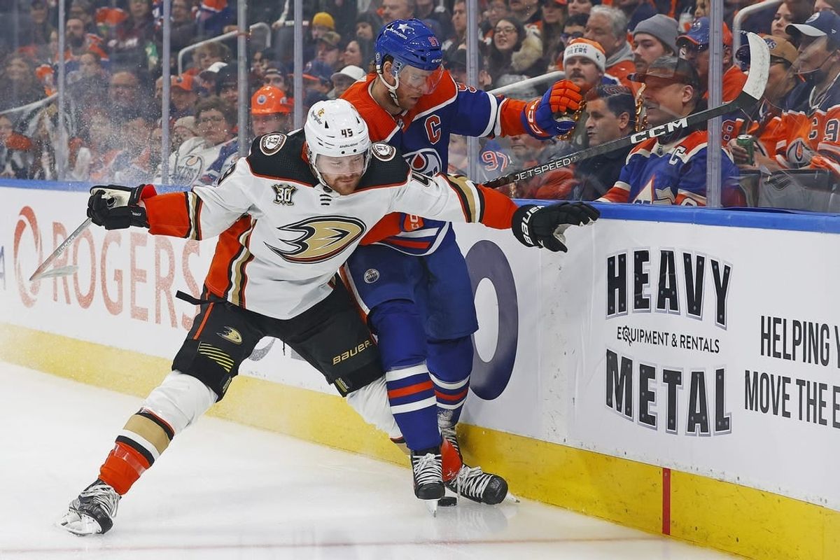 Nov 26, 2023; Edmonton, Alberta, CAN; Anaheim Ducks forward Max Jones (49) and Edmonton Oilers forward Connor McDavid (97) battle along the boards for a loose puck during the first period at Rogers Place.
