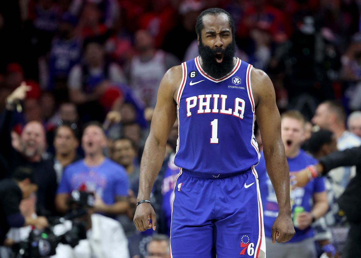 A Black man with a large beard in a blue basketball uniform with white and red detailing yells in the middle of an NBA basketball game.