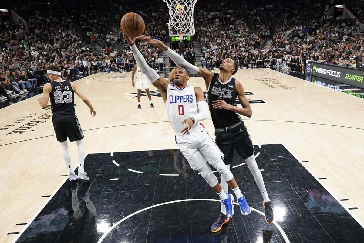 Nov 22, 2023; San Antonio, Texas, USA; Los Angeles Clippers guard Russell Westbrook (0) lays in a basket while defended by San Antonio Spurs forward Victor Wembanyama (1) during the second half at Frost Bank Center.