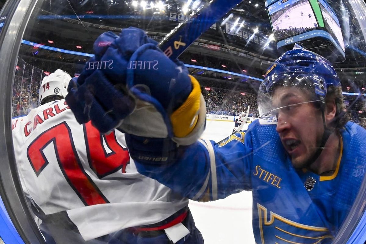 Jan 20, 2024; St. Louis, Missouri, USA;  St. Louis Blues left wing Jake Neighbours (63) checks Washington Capitals defenseman John Carlson (74) during the second period at Enterprise Center.