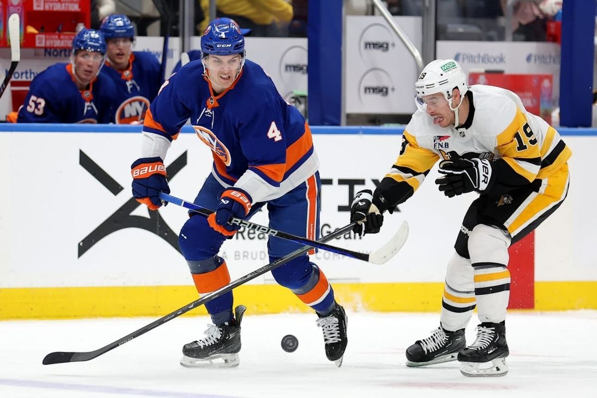 Dec 27, 2023; Elmont, New York, USA; New York Islanders defenseman Samuel Bolduc (4) fights for the puck against Pittsburgh Penguins right wing Reilly Smith (19) during the third period at UBS Arena.