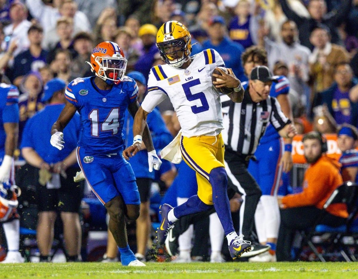 Nov 11, 2023; Baton Rouge, Louisiana, USA;  LSU Tigers quarterback Jayden Daniels (5) rushes for a touchdown against Florida Gators safety Jordan Castell (14) during the first half at Tiger Stadium.