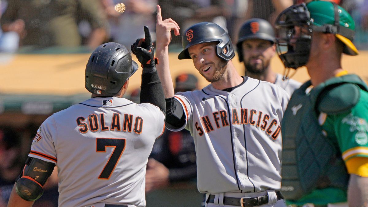 Donovan Solano and Austin Slater of the San Francisco Giants celebrate after Solano hit a pinch-hit two-run home run against the Oakland Athletics in the top of the eighth inning at RingCentral Coliseum.