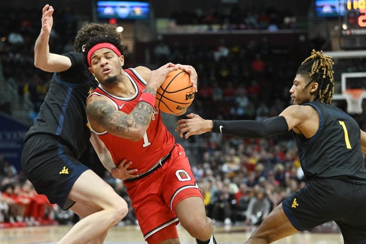 Dec 30, 2023; Cleveland, Ohio, USA; Ohio State Buckeyes guard Roddy Gayle Jr. (1) drives to the basket between West Virginia Mountaineers forward Ofri Naveh (9) and guard Noah Farrakhan (1) during the first half at Rocket Mortgage FieldHouse.
