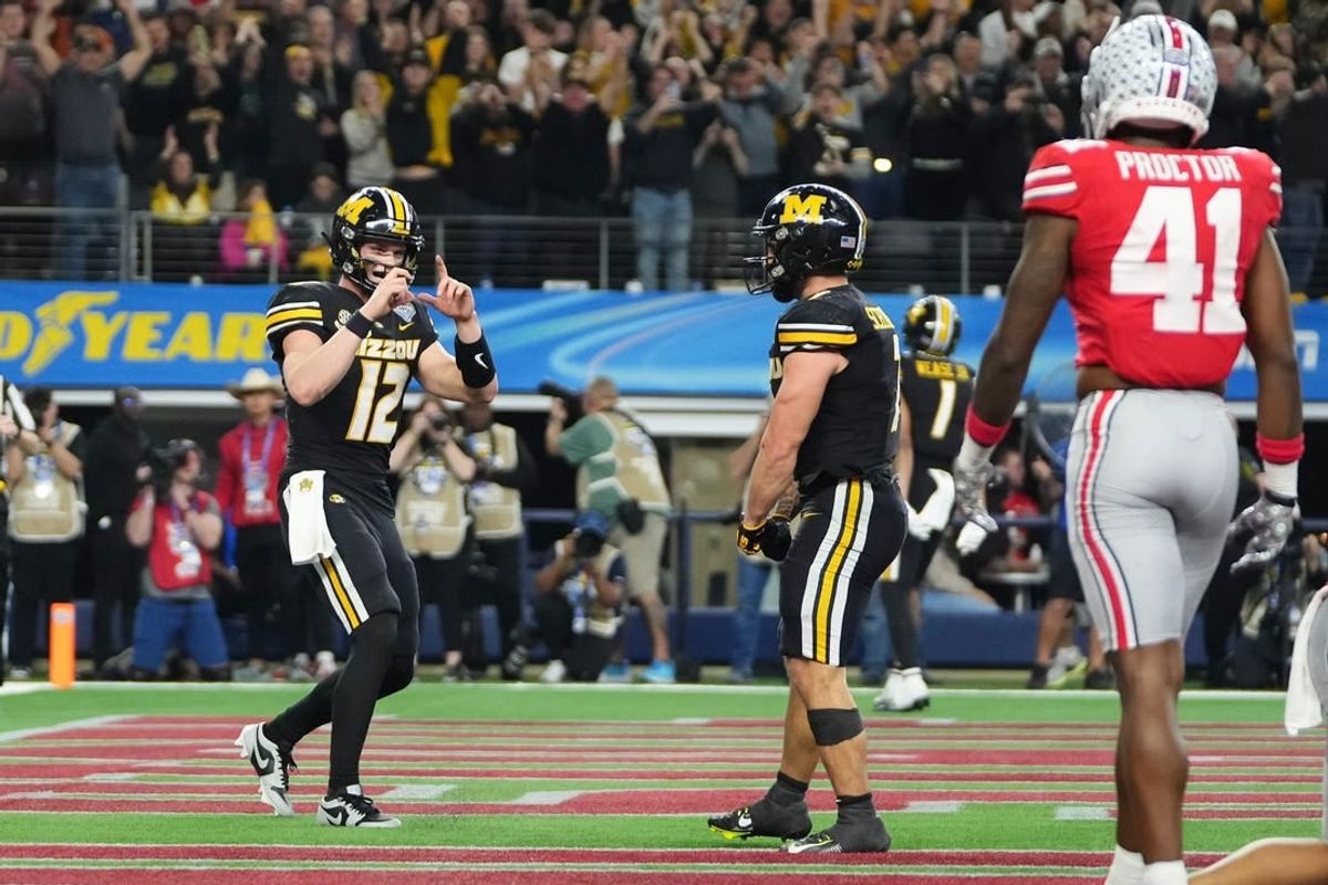 Dec 29, 2023; Arlington, Texas, USA; Missouri Tigers quarterback Brady Cook (12) pretends to take a photo of running back Cody Schrader (7) after he scored a touchdown during the third quarter of the Goodyear Cotton Bowl Classic against the Ohio State Buckeyes at AT&T Stadium. Ohio State lost 14-3.