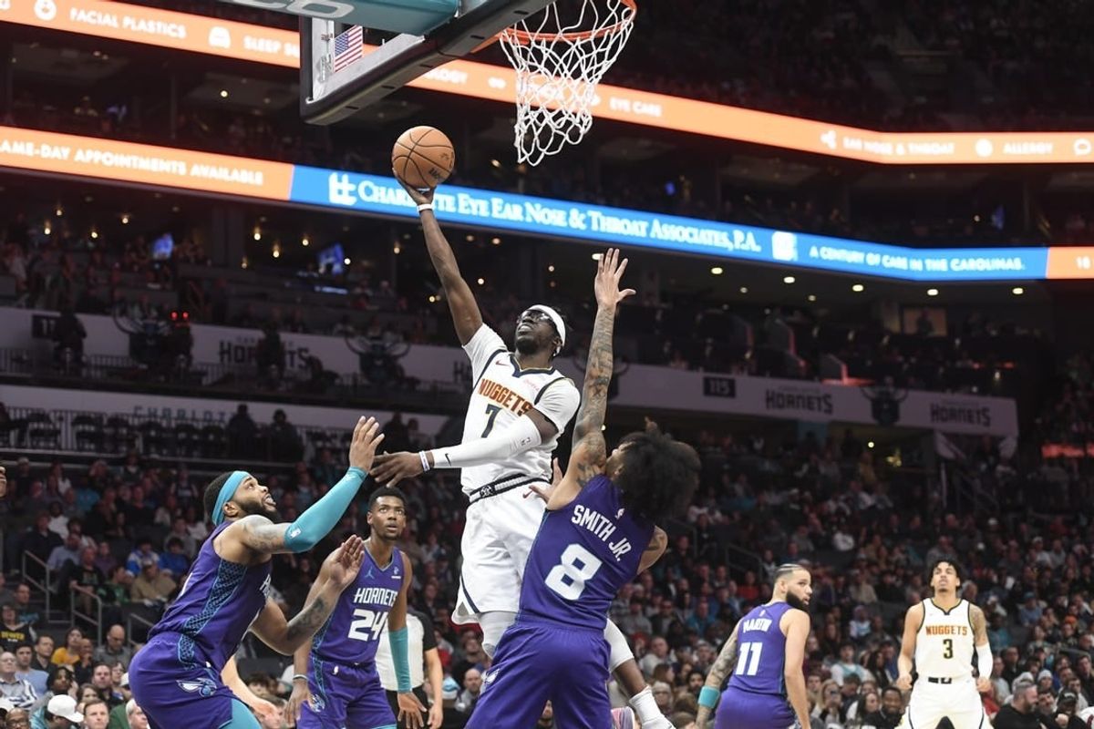 Dec 23, 2023; Charlotte, North Carolina, USA;  Denver Nuggets guard Reggie Jackson (7) drives against Charlotte Hornets forward Miles Bridges (0) and guard Nick Smith Jr. (8) during the first half at the Spectrum Center.