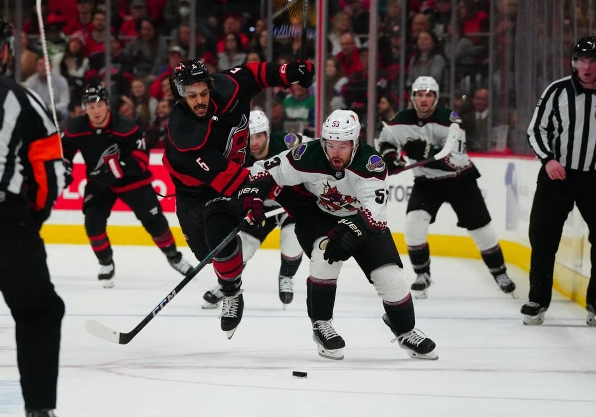 Jan 27, 2024; Raleigh, North Carolina, USA; Arizona Coyotes left wing Michael Carcone (53) and Carolina Hurricanes defenseman Jalen Chatfield (5) battle over the puck during the second period at PNC Arena.