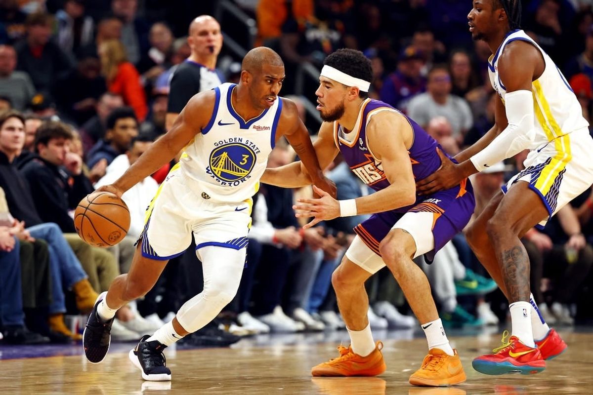 Dec 12, 2023; Phoenix, Arizona, USA; Golden State Warriors guard Chris Paul (3) drives to the basket against Phoenix Suns guard Devin Booker (1) during the first quarter at Footprint Center.