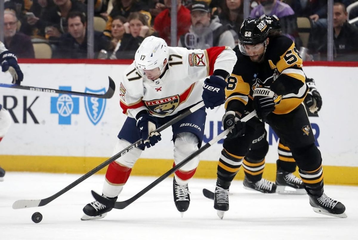 Jan 26, 2024; Pittsburgh, Pennsylvania, USA; Florida Panthers center Evan Rodrigues (17) moves the puck against pressure from Pittsburgh Penguins defenseman Kris Letang (58) during the second period at PPG Paints Arena.