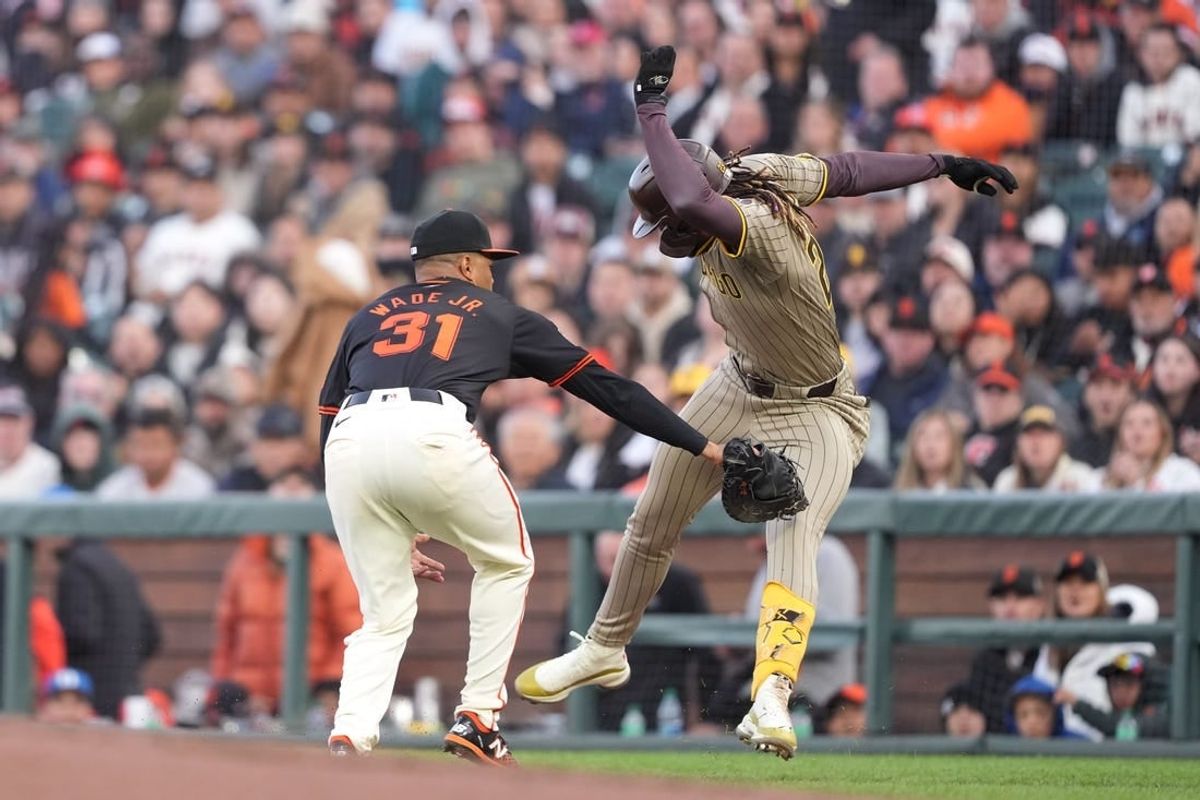 Apr 6, 2024; San Francisco, California, USA; San Diego Padres right fielder Fernando Tatis Jr. (right) is called safe after avoiding the tag of San Francisco Giants first baseman LaMonte Wade Jr. (31) for a single during the third inning at Oracle Park. The call was overturned to an out after a video review.