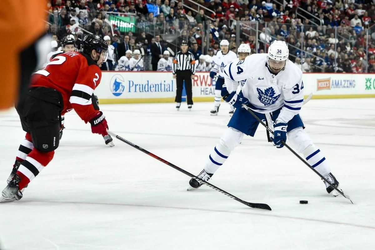 Apr 9, 2024; Newark, New Jersey, USA; Toronto Maple Leafs center Auston Matthews (34) skates with the puck while being defended by New Jersey Devils defenseman Brendan Smith (2) during the third period at Prudential Center.