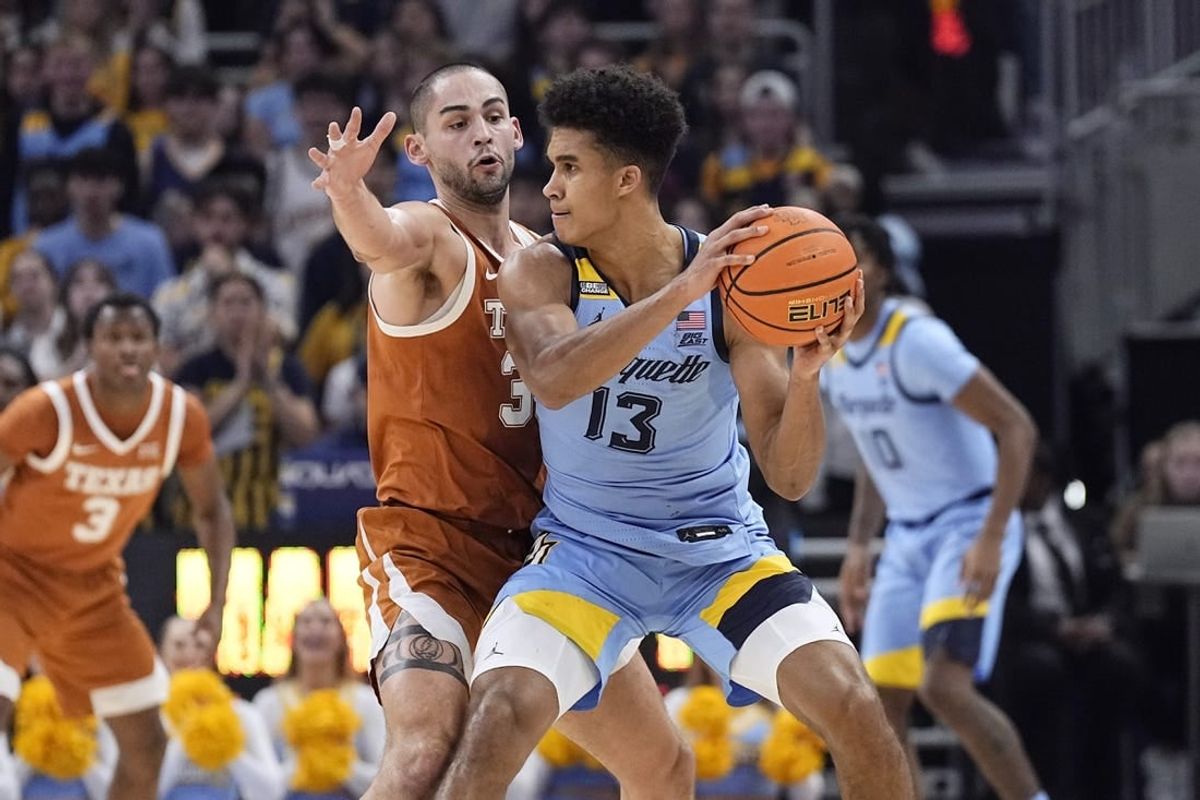 Dec 6, 2023; Milwaukee, Wisconsin, USA;  Marquette Golden Eagles forward Oso Ighodaro (13) looks to pass the ball under pressure from Texas Longhorns forward Brock Cunningham (30) during the first half at Fiserv Forum.