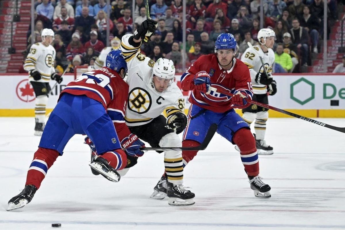 Nov 11, 2023; Montreal, Quebec, CAN; Boston Bruins forward Brad Marchand (63) splits Montreal Canadiens defenseman Justin Barron (52) and teammate forward Alex Newhook (15) during the first period at the Bell Centre.