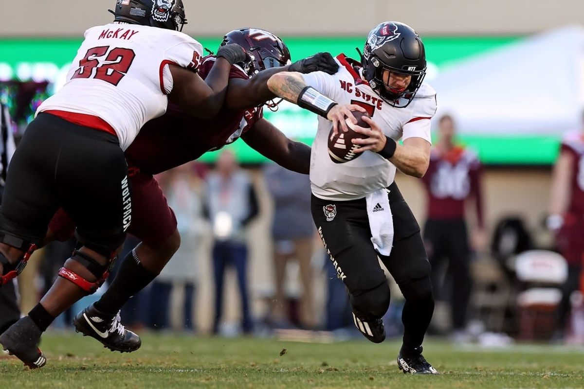 Nov 18, 2023; Blacksburg, Virginia, USA; North Carolina State Wolfpack quarterback Brennan Armstrong (5) runs from Virginia Tech Hokies defensive lineman Norell Pollard (3) during the second quarter at Lane Stadium.