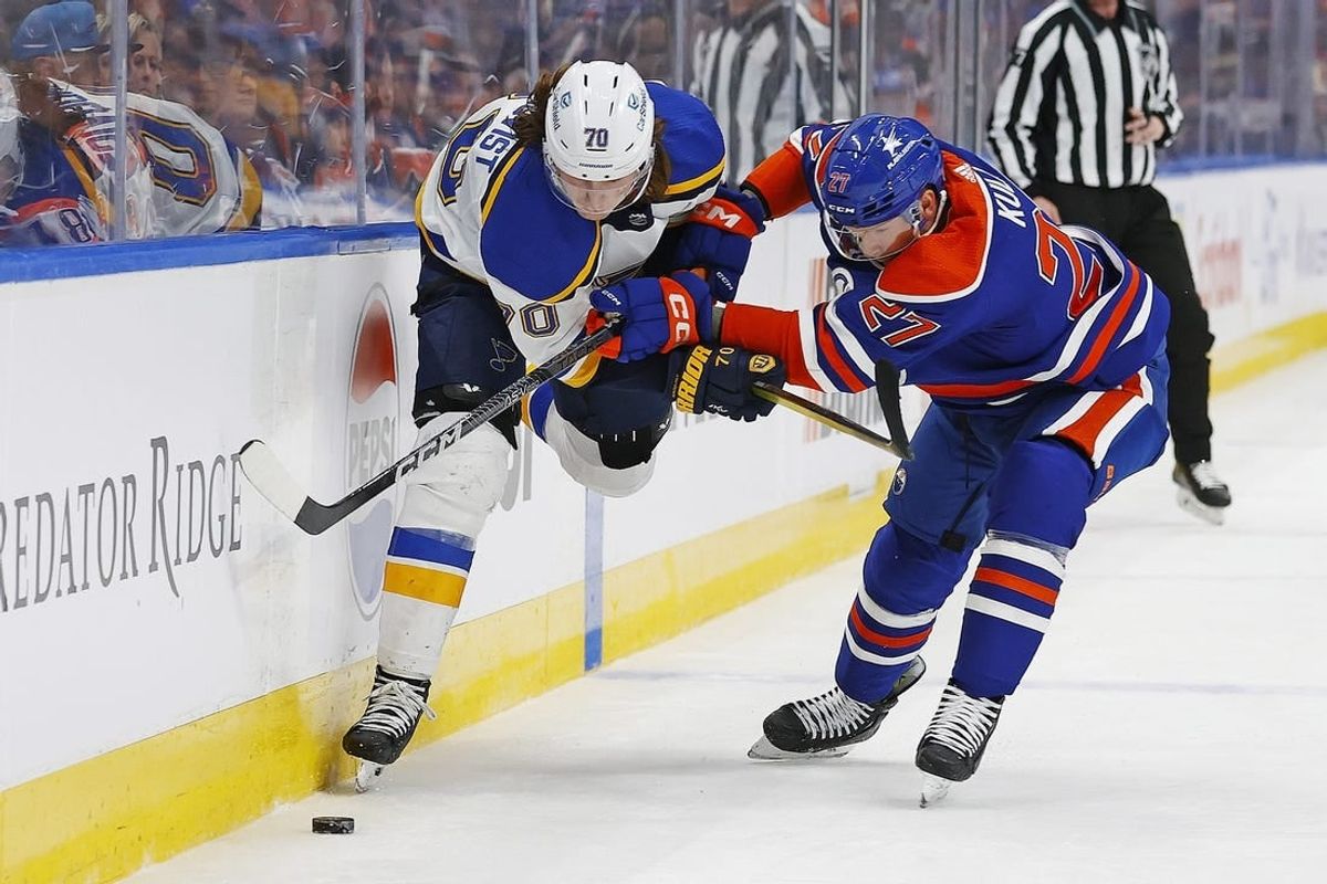 Feb 28, 2024; Edmonton, Alberta, CAN; St. Louis Blues forward Oskar Sundqvist (70) and Edmonton Oilers defensemen Brett Kulak (27)  battle for a loose puck  during the second period at Rogers Place.