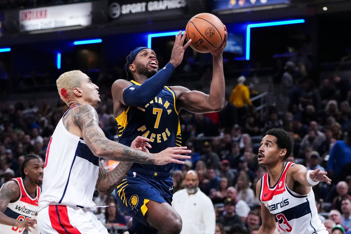 Buddy Hield attempts a shot while being guarded by Kyle Kuzma (l.) and Jordan Poole