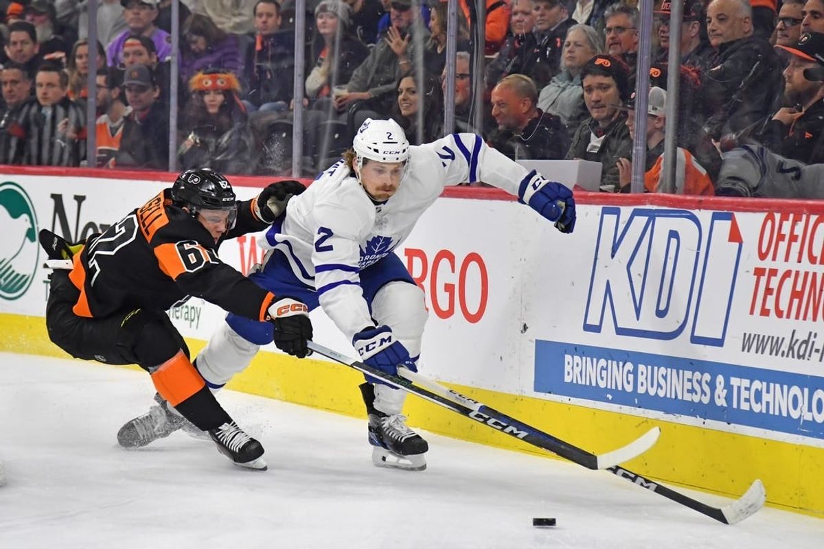 Mar 19, 2024; Philadelphia, Pennsylvania, USA; Toronto Maple Leafs defenseman Simon Benoit (2) and Philadelphia Flyers right wing Olle Lycksell (62) reach for the puck during the first period at Wells Fargo Center.