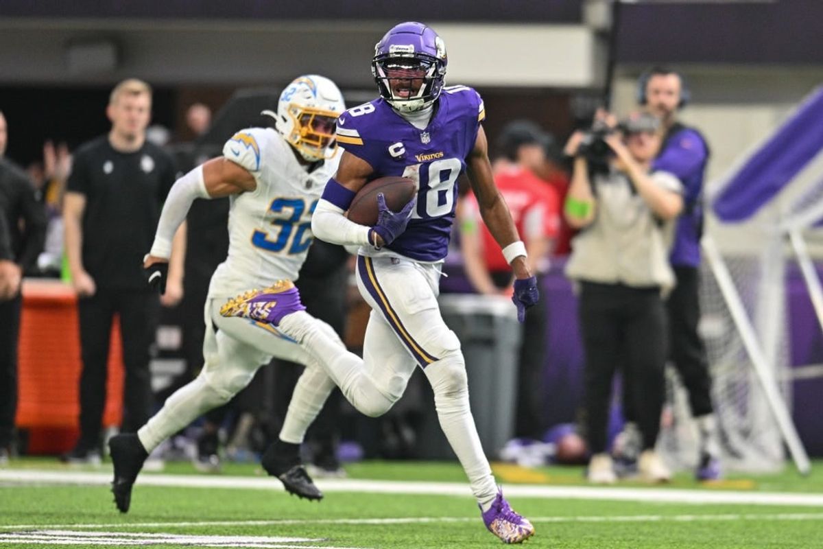 Sep 24, 2023; Minneapolis, Minnesota, USA; Minnesota Vikings wide receiver Justin Jefferson (18) scores on a touchdown pass as Los Angeles Chargers safety Alohi Gilman (32) chases from behind during the fourth quarter at U.S. Bank Stadium.