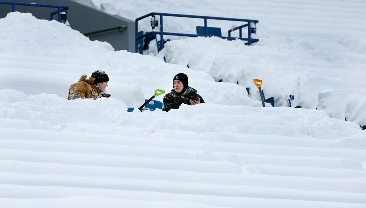 Shovelers take a break from clearing snow inside Highmark Stadium.
