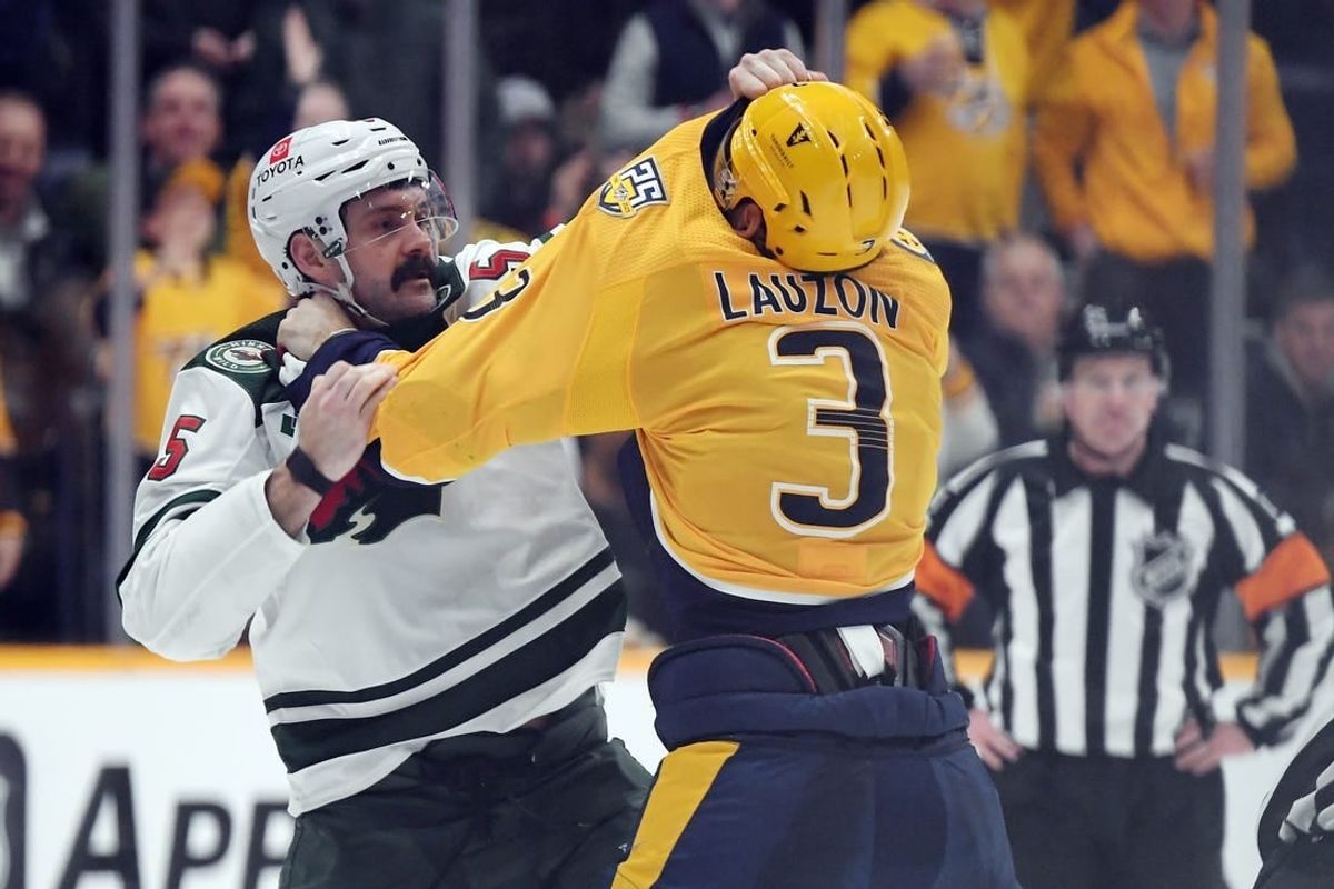 Feb 29, 2024; Nashville, Tennessee, USA; Minnesota Wild defenseman Jake Middleton (5) and Nashville Predators defenseman Jeremy Lauzon (3) exchange punches during a fight during the second period at Bridgestone Arena.