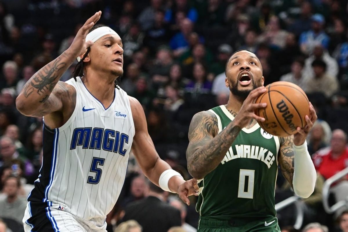 Apr 10, 2024; Milwaukee, Wisconsin, USA;  Milwaukee Bucks guard Damian Lillard (0) takes a shot against Orlando Magic forward Paolo Banchero (5) in the second quarter at Fiserv Forum.