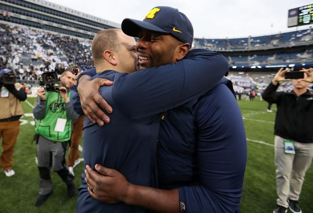 Nov 11, 2023; University Park, Pennsylvania, USA; Michigan Wolverines offensive line coach Sherrone Moore hugs an assistant coach following a game against the Penn State Nittany Lions at Beaver Stadium. Michigan won 24-15.