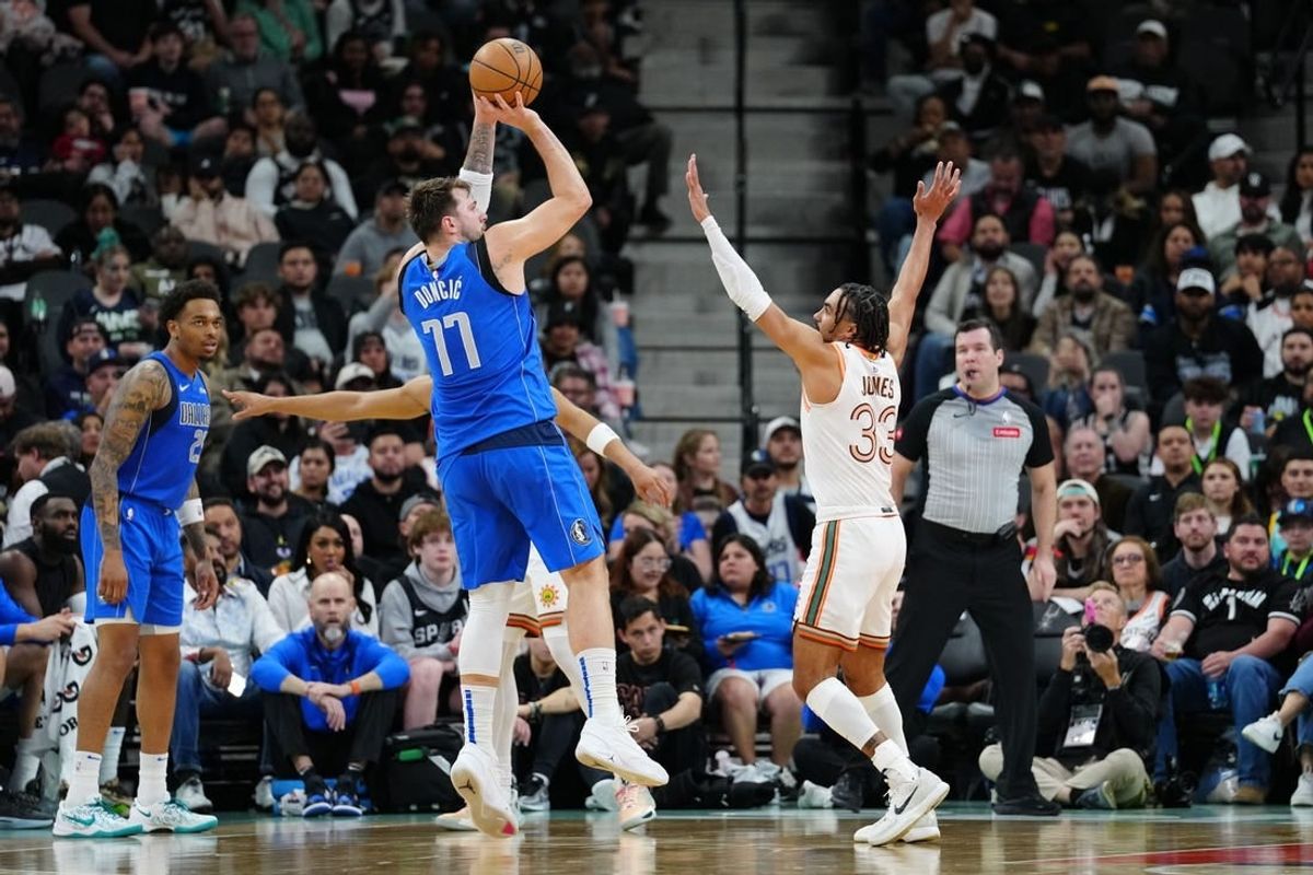 Mar 19, 2024; San Antonio, Texas, USA;  Dallas Mavericks guard Luka Doncic (77) shoots over San Antonio Spurs guard Tre Jones (33) in the first half at Frost Bank Center.