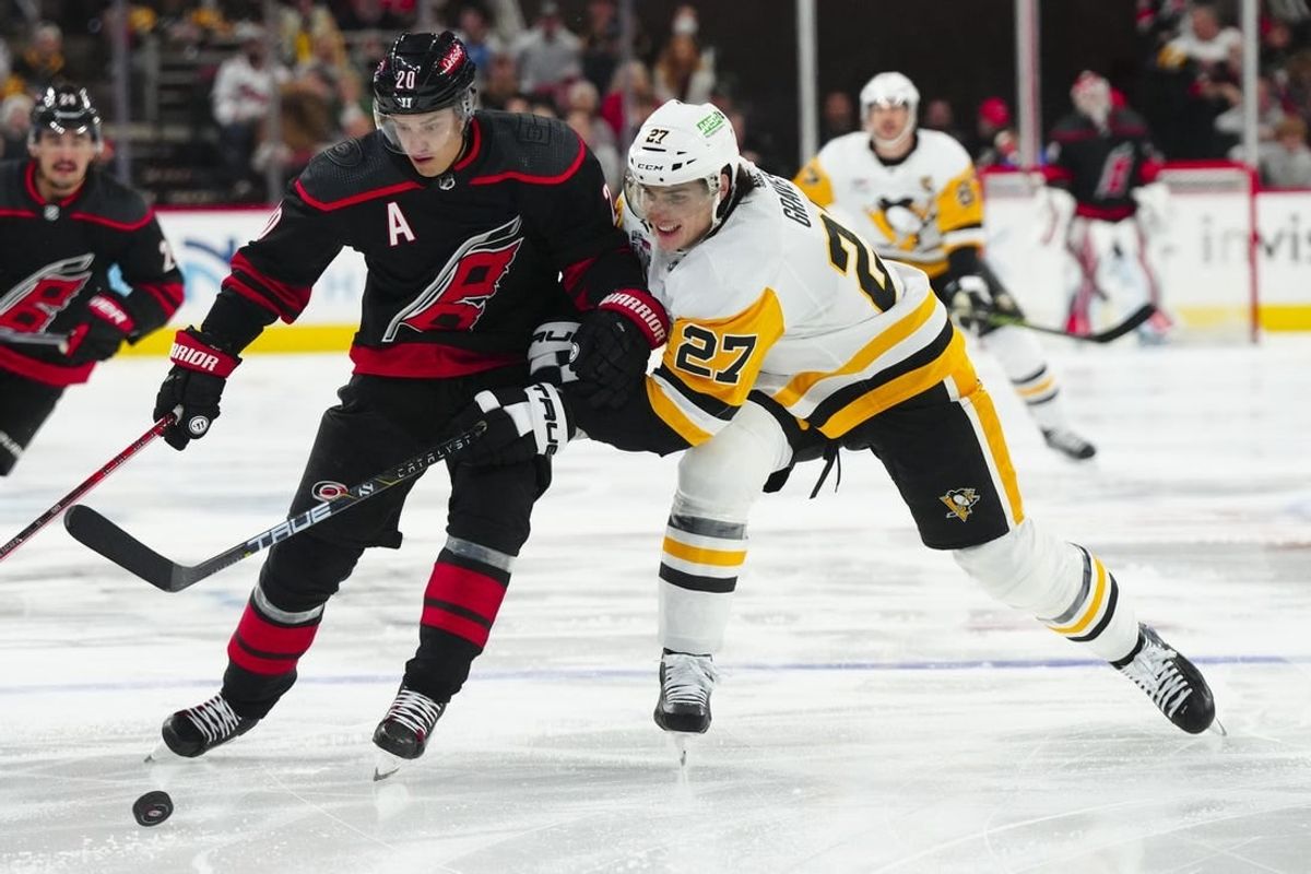 Nov 18, 2023; Raleigh, North Carolina, USA; Carolina Hurricanes center Sebastian Aho (20) tries to control the puck against Pittsburgh Penguins defenseman Ryan Graves (27) during the first period at PNC Arena.
