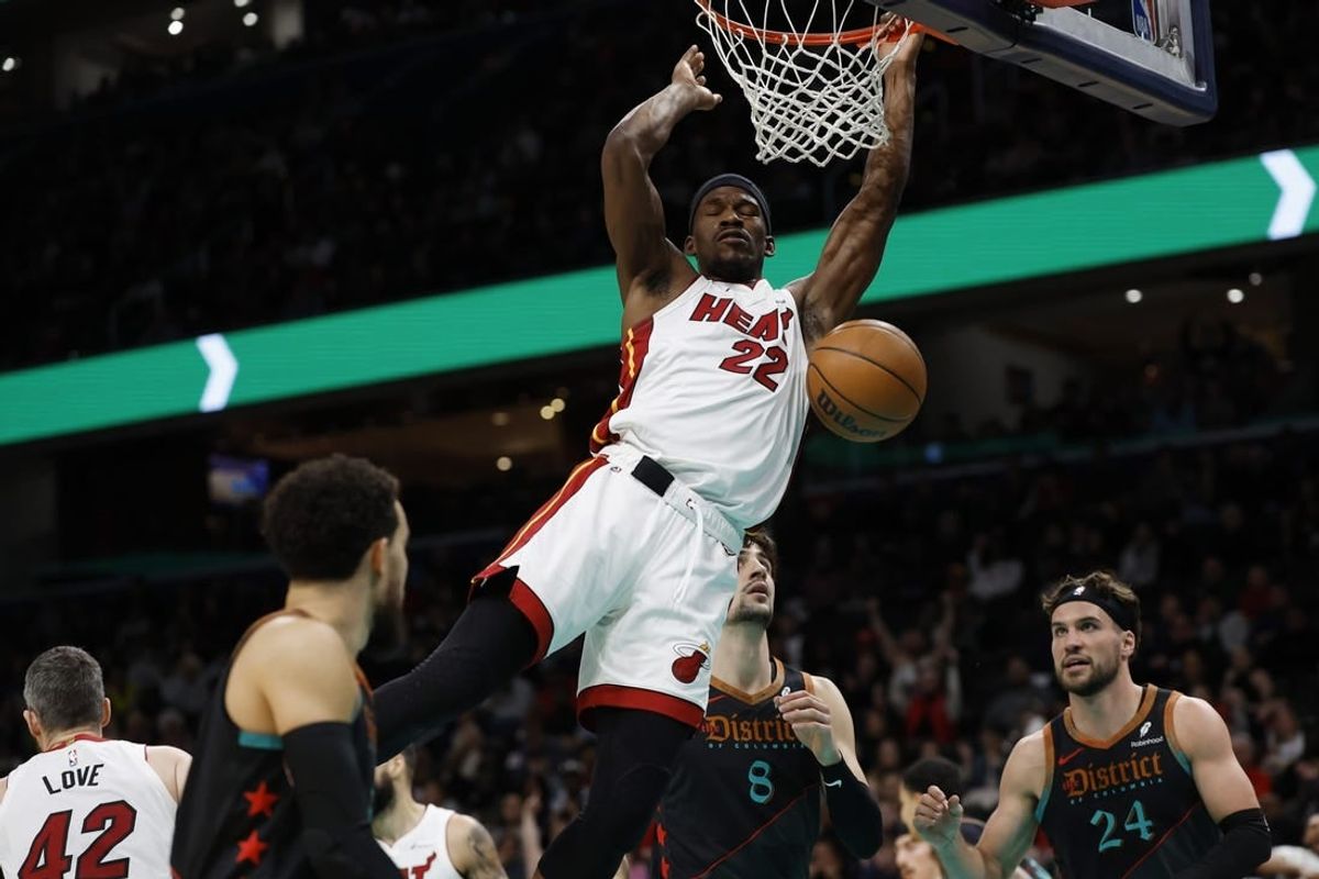 Feb 2, 2024; Washington, District of Columbia, USA; Miami Heat forward Jimmy Butler (22) dunks the ball as Washington Wizards forward Deni Avdija (8) looks on in the first half at Capital One Arena.