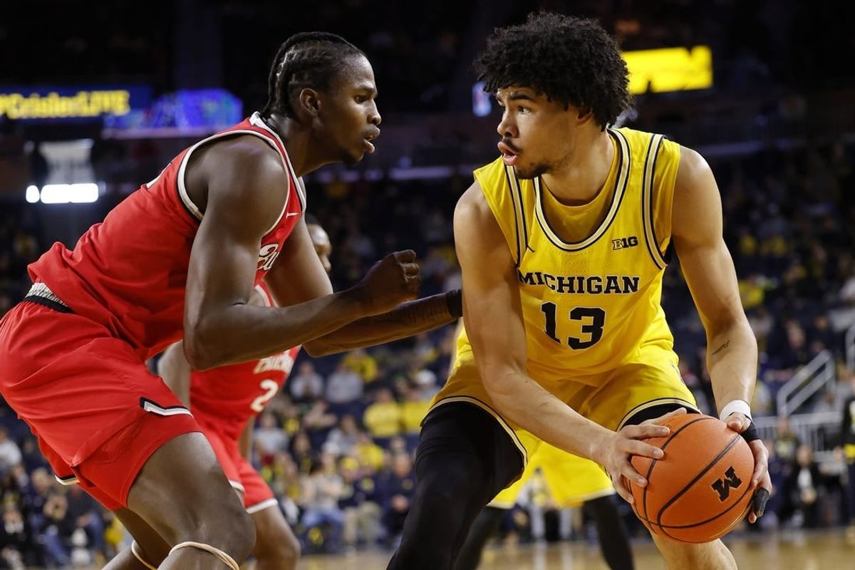Jan 15, 2024; Ann Arbor, Michigan, USA; Michigan Wolverines forward Olivier Nkamhoua (13) dribbles as Ohio State Buckeyes center Felix Okpara (34) defends in the first half at Crisler Center.
