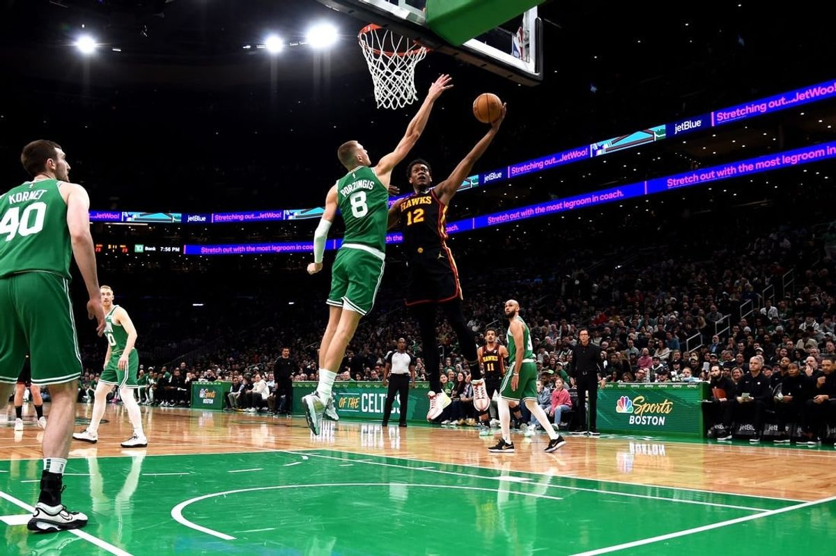 Feb 7, 2024; Boston, Massachusetts, USA;  Atlanta Hawks forward De'Andre Hunter (12) drives to the basket and gets fouled by Boston Celtics center Kristaps Porzingis (8) during the first half at TD Garden.