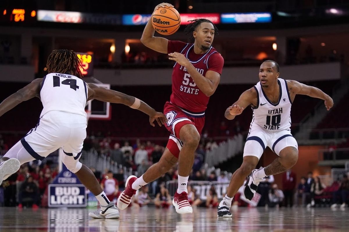 Feb 27, 2024; Fresno, California, USA; Fresno State Bulldogs guard Xavier DuSell (53) drives past Utah State Aggies guard Josh Uduje (14) and guard Darius Brown II (10) in overtime at the Save Mart Center.