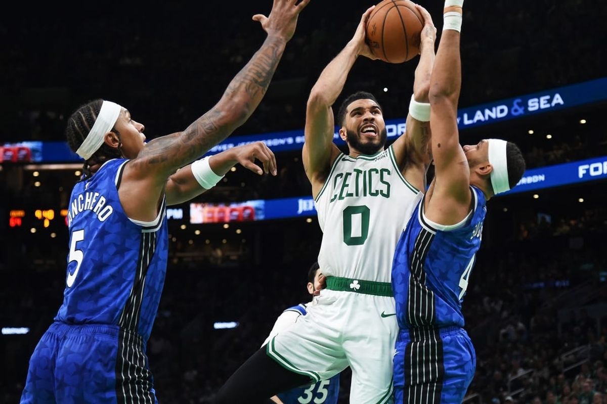 Dec 17, 2023; Boston, Massachusetts, USA;  Boston Celtics forward Jayson Tatum (0) drives to the basket between Orlando Magic forward Paolo Banchero (5) and guard Jalen Suggs (4) during the second half at TD Garden.