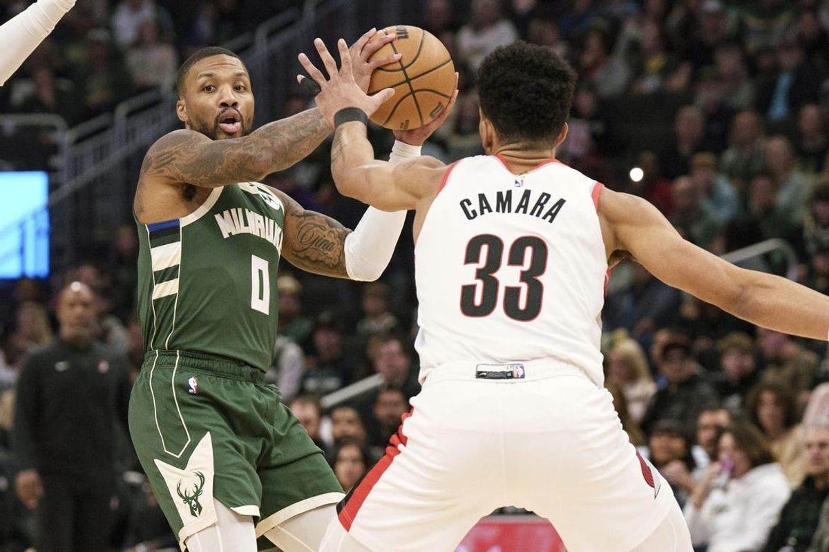 Nov 26, 2023; Milwaukee, Wisconsin, USA;  Milwaukee Bucks guard Damian Lillard (0) looks to pass the ball under pressure from Portland Trail Blazers forward Toumani Camara (33) during the first quarter at Fiserv Forum.