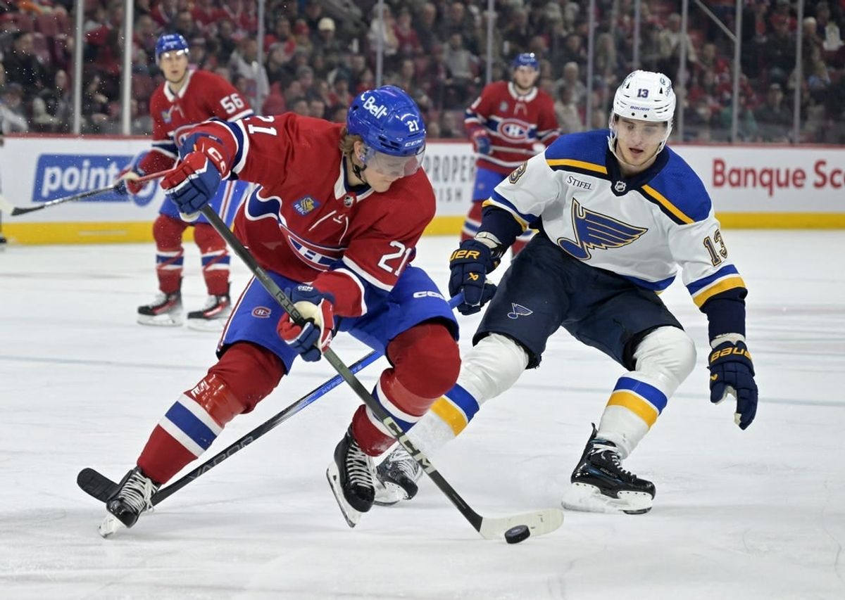 Feb 11, 2024; Montreal, Quebec, CAN; Montreal Canadiens defenseman Kaiden Guhle (21) plays the puck and St.Louis Blues forward Alexey Toropchenko (13) forechecks during the first period at the Bell Centre.