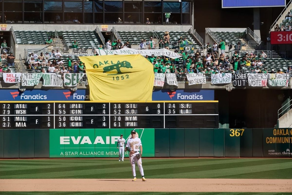 Sep 24, 2023; Oakland, California, USA; Fans in the outfield bleachers display homemade signs critical of the MLB Commissioner and Oakland Athletics ownership and Oakland Athletics infielder Zack Gelof (20) and outfielder Brent Rooker (25) stand on the field during the eighth inning against the Detroit Tigers at Oakland-Alameda County Coliseum.