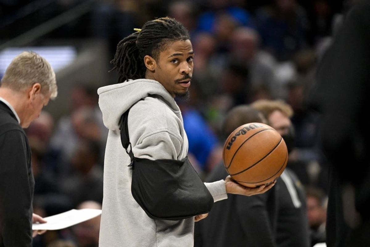 Jan 9, 2024; Dallas, Texas, USA; Memphis Grizzlies guard Ja Morant (12) looks on while wearing his arm in a sling during a time stoppage in the first quarter of the game between the Dallas Mavericks and the Memphis Grizzlies at the American Airlines Center.