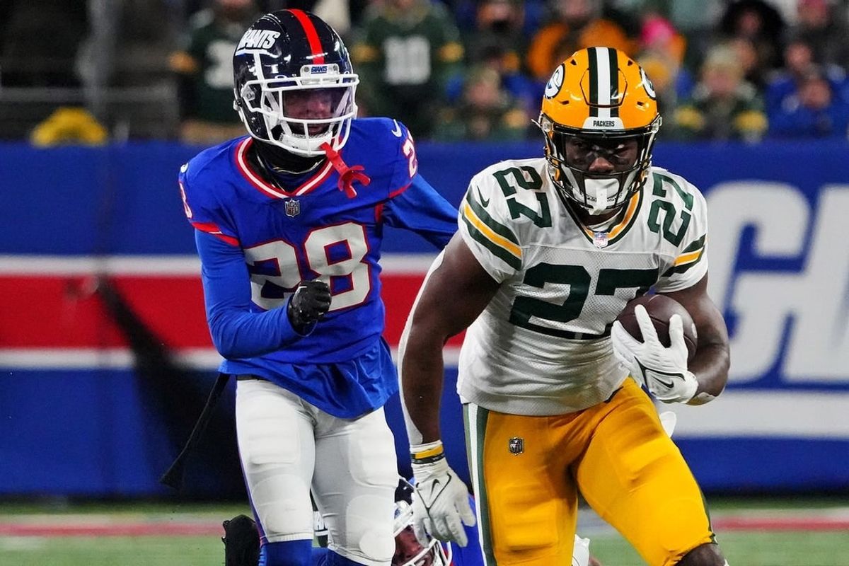 Dec 11, 2023; East Rutherford, New Jersey, USA; Green Bay Packers running back Patrick Taylor (27) runs the ball against New York Giants cornerback Cor'Dale Flott (28) during the second quarter at MetLife Stadium.